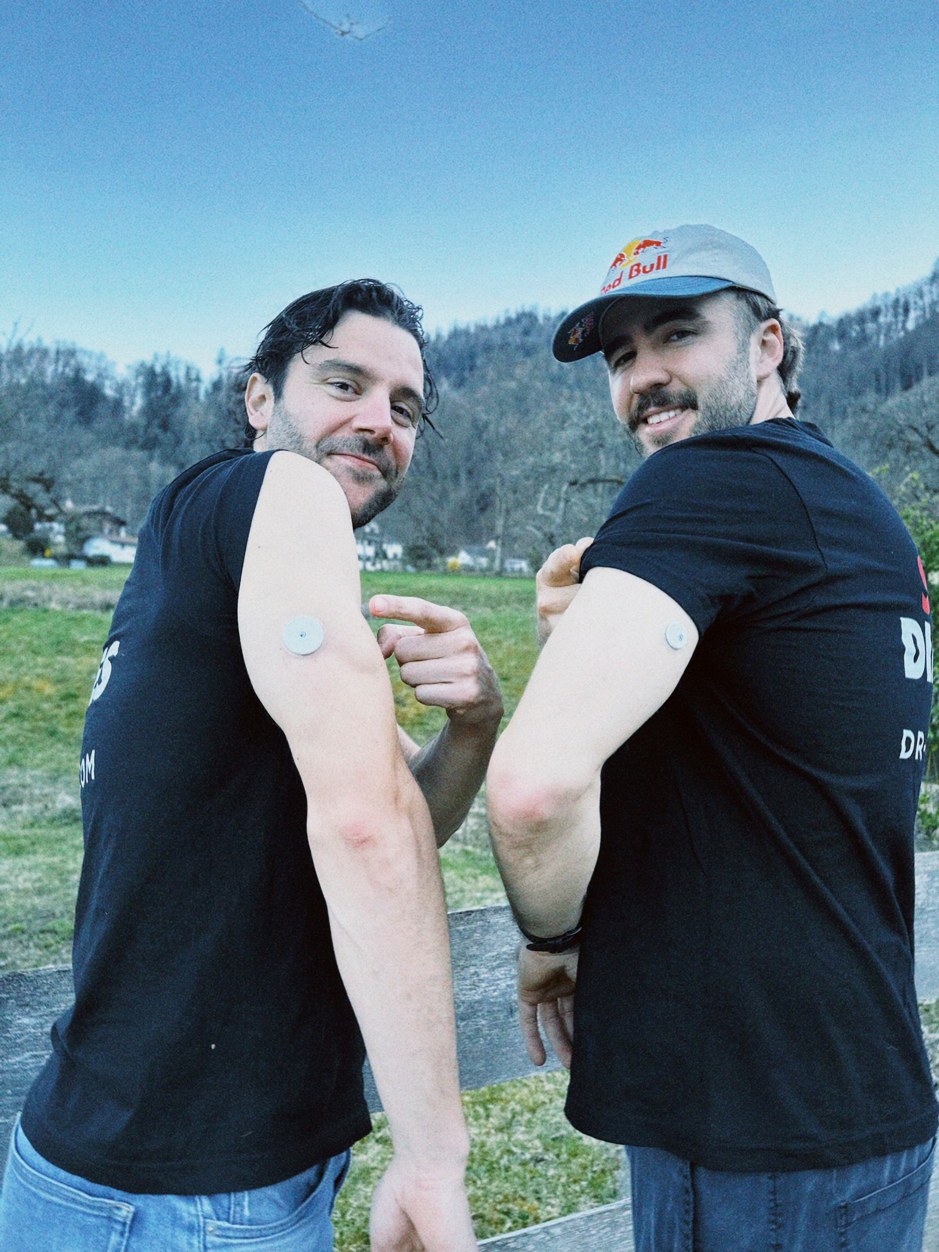 Pedro Dias and Manuel Lettenbichler showing their glucose sensors outdoors.